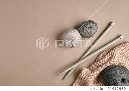 Knitted from a gray yarn sweater and thread for knitting closeup. Knitting as a hobby. Accessories for knitting. 91412980