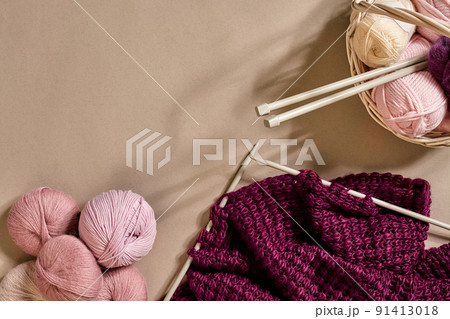 Balls of merino wool yarn, knitting on knitting needles on a beige surface. Top view 91413018