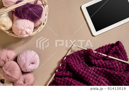 Balls of merino wool yarn, knitting on knitting needles on a beige surface. Top view 91413019