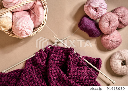 Balls of merino wool yarn, knitting on knitting needles on a beige surface. Top view 91413030