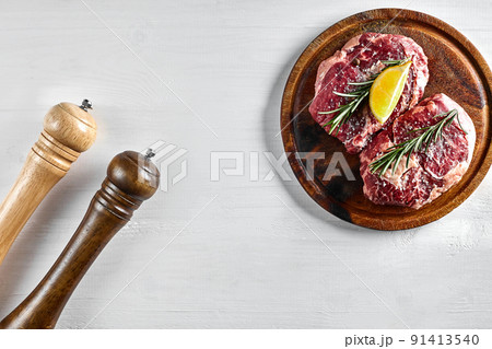 Raw beef steak with spices and ingredients for cooking on wooden cutting board and white background. 91413540