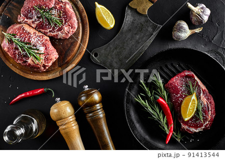 Fresh raw meat. Beef Tenderloin and marbled beef steaks on grill pan and frying board with seasoning, black background top view. Fresh raw meat. Beef Tenderloin and marbled beef steaks on grill pan and frying board with seasoning, black background top view. 91413544