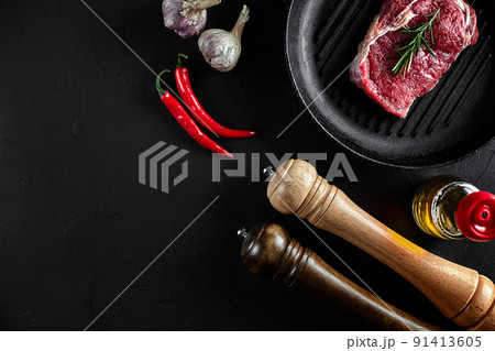 Fresh raw meat. Beef Tenderloin and marbled beef steaks on grill pan and frying board with seasoning, black background top view. 91413605