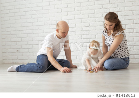 Baby child with hearing aids and cochlear implants plays with parents on floor. Deaf and rehabilitation concept Baby child with hearing aids and cochlear implants plays with parents on floor. Deaf and rehabilitation concept 91413613