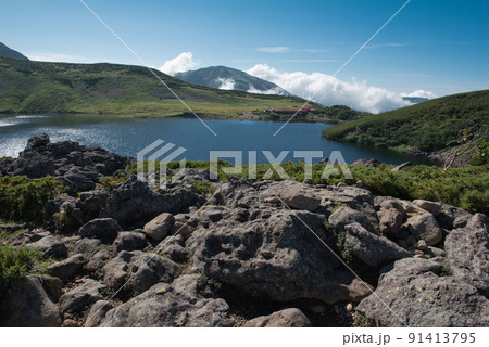 長野県富山県にある日本百名山の白馬岳への白馬大池付近の白馬大池山荘と雪渓と雲と青空の景色 長野県富山県にある日本百名山の白馬岳への白馬大池付近の白馬大池山荘と雪渓と雲と青空の景色 91413795
