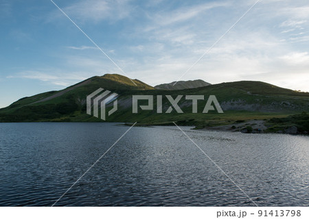 長野県富山県にある日本百名山の白馬岳への白馬大池付近の雪渓と三国境小蓮華山船越ノ頭方向の夕焼けと青空 91413798