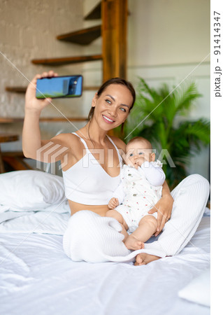 A woman shows their daughter to dad, smiles and communicates with her husband. A woman shows their daughter to dad, smiles and communicates with her husband. 91414347