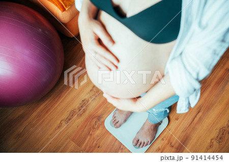 Pregnant weights woman belly. Happy pregnancy woman standing on weight scales. Pregnancy, medicine health care concept. Pregnant weights woman belly. Happy pregnancy woman standing on weight scales. Pregnancy, medicine health care concept. 91414454