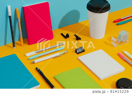 Colorful notepads, pens and paper cup on orange table 91415229