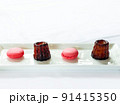 お皿にのったカヌレとピンクのマカロン - かわいいデザート･スイーツの素材 91415350