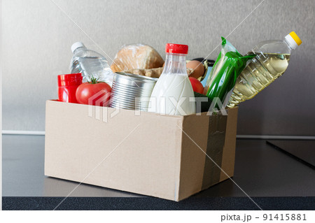 Various food, bottle of oil, milk and water, fresh vegetables in a cardboard box. Food donations or food safe delivery concept. 91415881