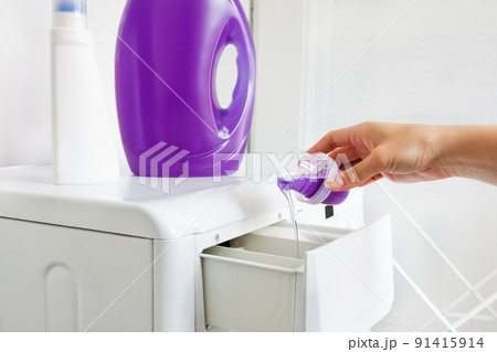 Woman hand pouring liquid detergent in the washing machine. 91415914