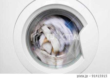 Laundry washing clothes rotating in machine drum front view. 91415915