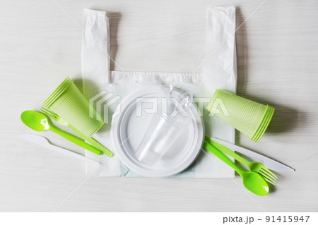 Plastic disposable dishes. Food plastic on wooden background top view. Recycling plastic and ecology concept. Plastic waste. 91415947