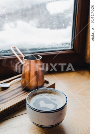 Hot coffee in the cup near the window with winter view Hot coffee in the cup near the window with winter view 91417026
