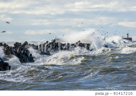 coastal storm in the baltic sea, big waves crash against the harbor breakwater 91417210