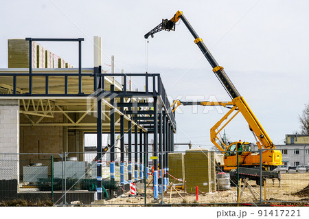 Telescopic boom crane and self propelled lift at metal construction frames assemblage Telescopic boom crane and self propelled lift at metal construction frames assemblage 91417221