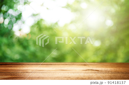 Blank country fence plank, table top or counter bar with abstract green forest trees background. Nature bokeh sunlight. Mock up, product template. Banner or header for advertise on social media Blank country fence plank, table top or counter bar with abstract green forest trees background. Nature bokeh sunlight. Mock up, product template. Banner or header for advertise on social media 91418137