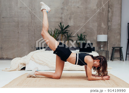 Fit woman doing bodyweight glute leg exercise kneeling leg raise lift 91419990