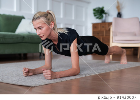 Woman doing plank exercise working out at home 91420007