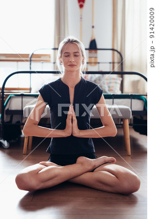 Woman doing yoga exercise at home . Fit woman meditating in lotus pose. Woman doing yoga exercise at home . Fit woman meditating in lotus pose. 91420009