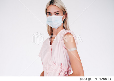 Woman showing her arm with bandage after receiving vaccination. 91420013