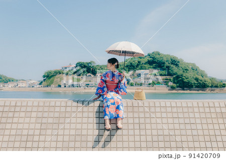 浴衣姿の女性と夏空の観光地 91420709