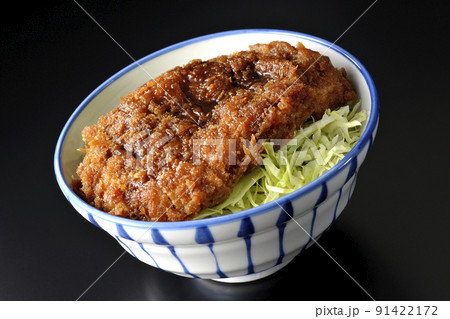繊切りキャベツの上にたっぷりのソースが絡んだカツが乗っているソースかつ丼を黒背景で撮影 91422172