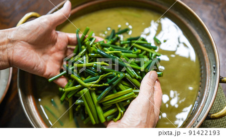 銅鍋と灰汁で山採り天然わらびのあく抜きをするシニア女性の手元 91422193