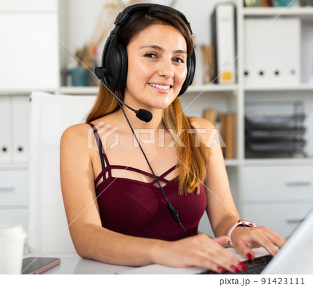 Young woman call centre operator with headphones in office Young woman call centre operator with headphones in office 91423111