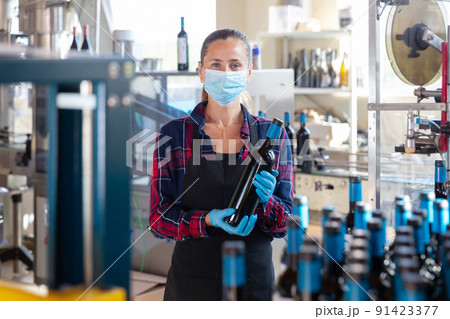 Worker of winery posing with bottled wine 91423377