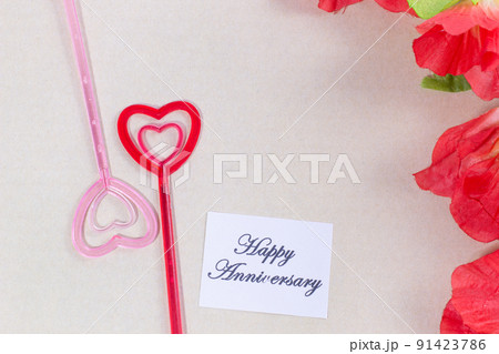 The plastic heart pairs with the happy anniversary card, with many flowers, brown background 91423786