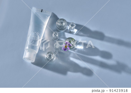 Transparent bottle of cosmetic gel on a blue background with small bottles of water. 91423918