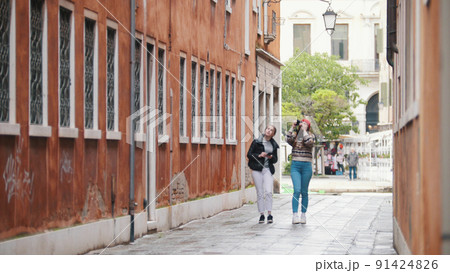 Two young women travelers walking on the narrow streets of Venice, Italy 91424826