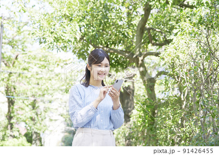 屋外での笑顔でスマホを使う女性 91426455