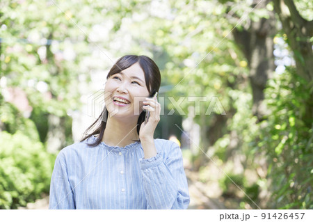 屋外での笑顔でスマホで電話する女性 91426457