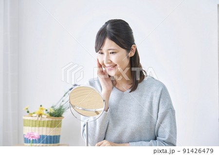 リビングで鏡を見て笑う女性 91426479