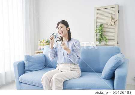 リビングで一人でテレビゲームをしてガッツポーズをする女性 リビングで一人でテレビゲームをしてガッツポーズをする女性 91426483