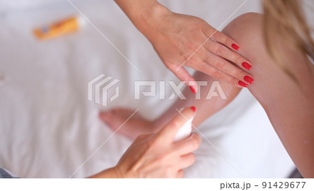 Mom puts sunscreen on daughter feet closeup 91429677