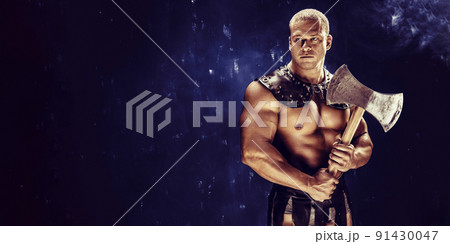 Studio shot of muscular ancient warrior man posing with axe Studio shot of muscular ancient warrior man posing with axe 91430047