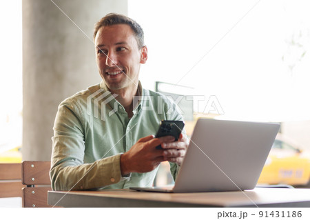 Confident businessman using smartphone sitting in restaurant Confident businessman using smartphone sitting in restaurant 91431186