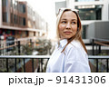 Portrait of young office woman standing on balcony enjoying city view 91431306