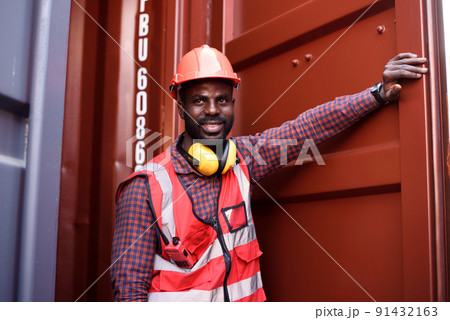 Happy African-American male engineer smiling when he standing at container warehouse, Worker get social security and insurance, Labor day and success business concept. Happy African-American male engineer smiling when he standing at container warehouse, Worker get social security and insurance, Labor day and success business concept. 91432163