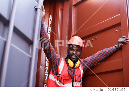 Happy African-American male engineer smiling when he standing at container warehouse, Worker get social security and insurance, Labor day and success business concept. Happy African-American male engineer smiling when he standing at container warehouse, Worker get social security and insurance, Labor day and success business concept. 91432165