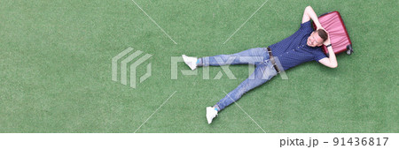 Young man lies on suitcase top view Young man lies on suitcase top view 91436817