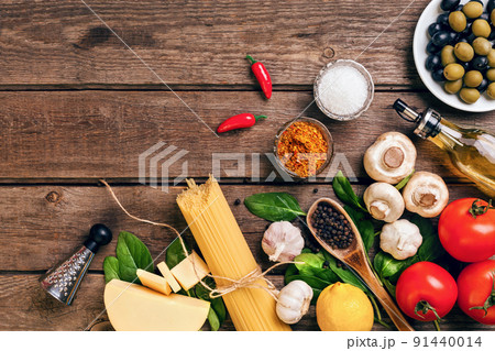 Pasta ingredients - tomatoes, olive oil, garlic, italian herbs, fresh basil, salt and spaghetti on a wooden background with copy space, horizontal, top view 91440014
