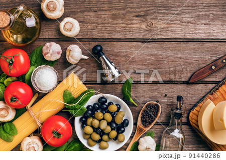 Raw ingredients for the preparation of Italian pasta, spaghetti, basil, tomatoes, olives and olive oil on wooden background. Top view. Copy space. Raw ingredients for the preparation of Italian pasta, spaghetti, basil, tomatoes, olives and olive oil on wooden background. Top view. Copy space. 91440286