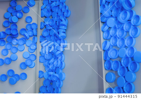 Many blue plastic bottle caps moving on conveyor belt - production line 91444315