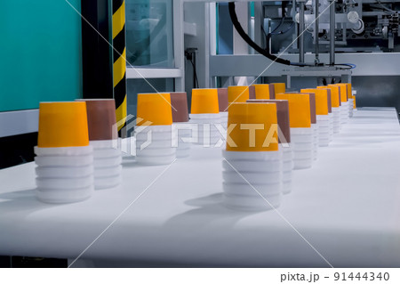 Empty yellow and brown plastic cups moving on conveyor belt at exhibition Empty yellow and brown plastic cups moving on conveyor belt at exhibition 91444340