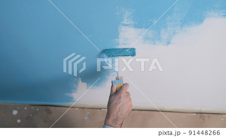 Man paints white wall with blue dye closeup Man paints white wall with blue dye closeup 91448266